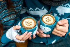 Couple holding knitted coffee cups dressed in sweater